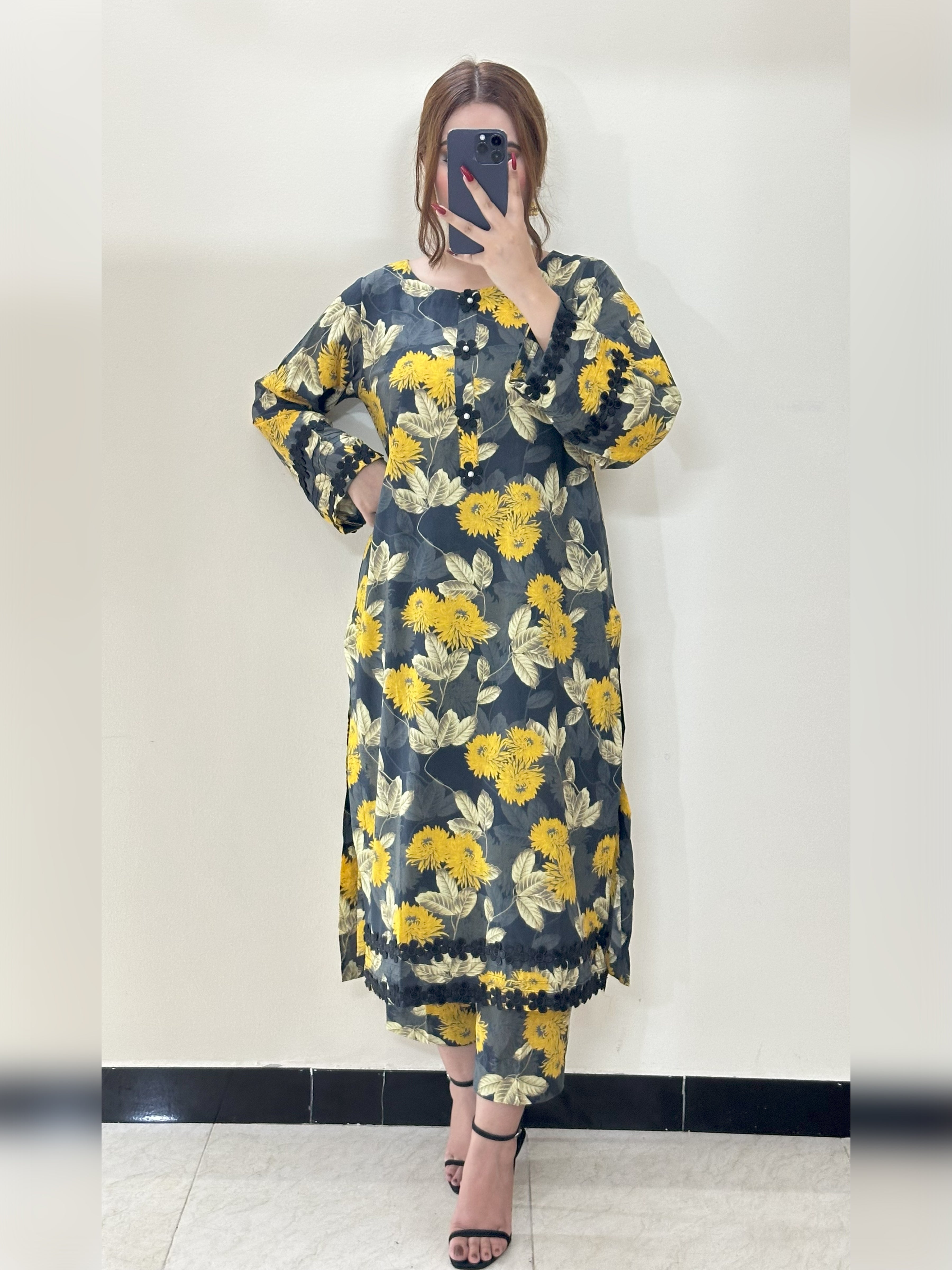 Person wearing a floral dress with yellow flowers on a plain background